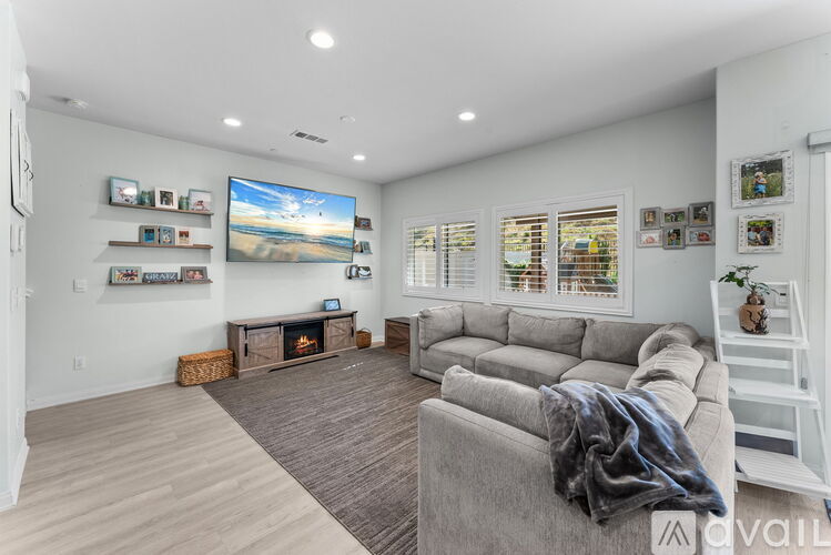 A living room with a grey couch and a television on the wall.