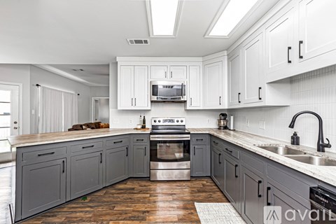 A kitchen with white cabinets and a wooden floor.