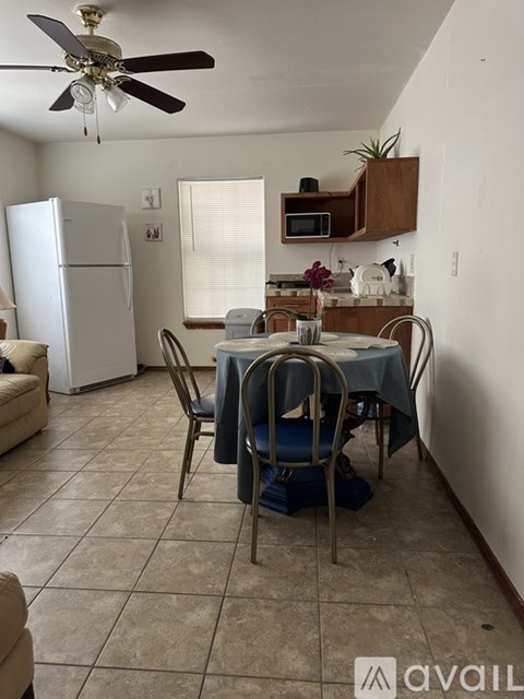 A kitchen with a table set for two and a fan on the ceiling.