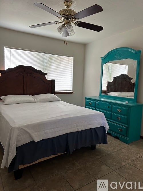 A bedroom with a bed, dresser, and mirror.