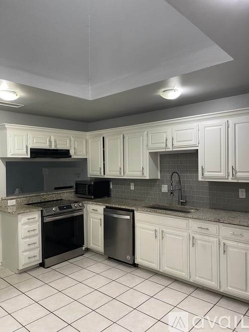 A kitchen with white cabinets and a black stove top oven.