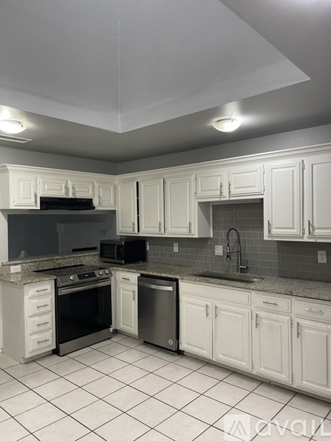 A kitchen with white cabinets and a black stove top oven.