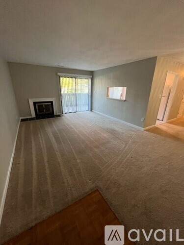 A living room with a carpeted floor and a fireplace.
