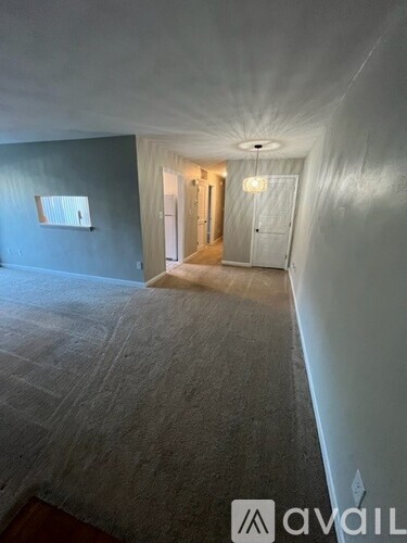 A room with a carpeted floor and a window on the left side.