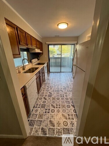 A kitchen with a tiled floor and wooden cabinets.