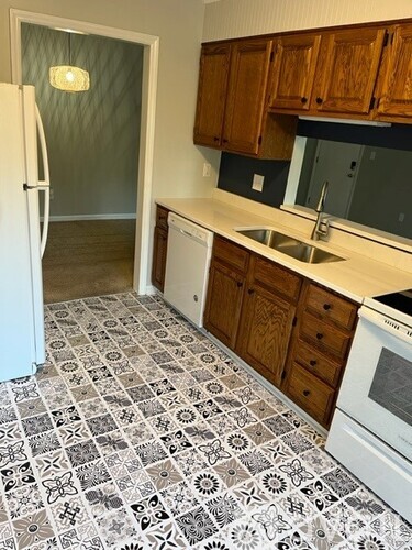 A kitchen with a white fridge and a patterned floor.