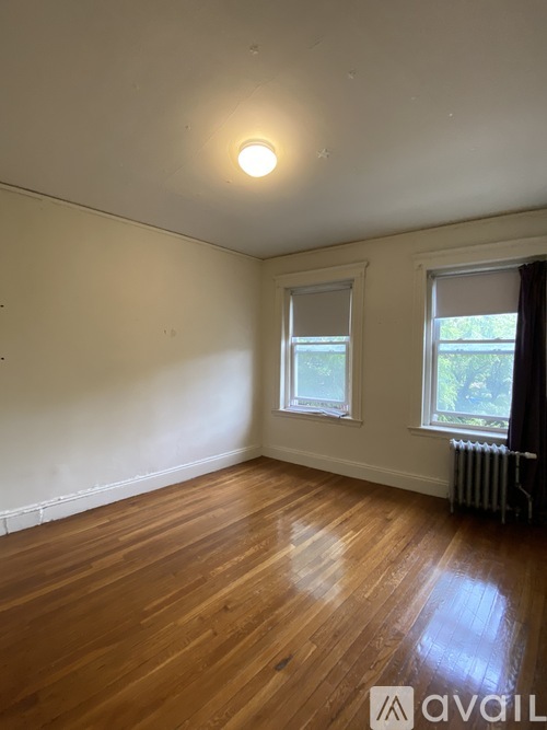 A room with wooden floors and two windows.