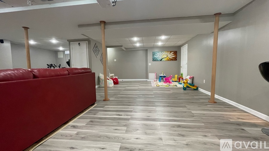 A spacious room with a red couch and wooden pillars.