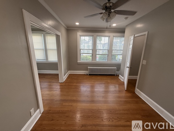 A spacious room with wooden floors and a ceiling fan.