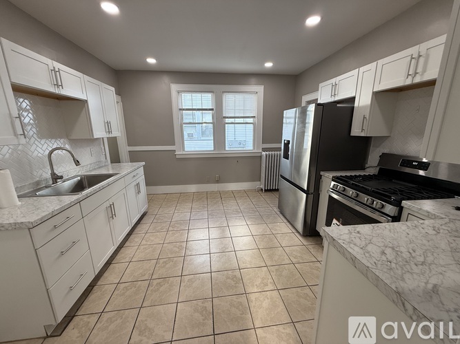 A kitchen with white cabinets and a tiled floor.