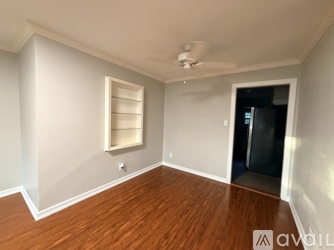 A room with a ceiling fan and a door leading to a dark space.