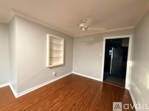 A room with a ceiling fan and a door leading to a dark space.