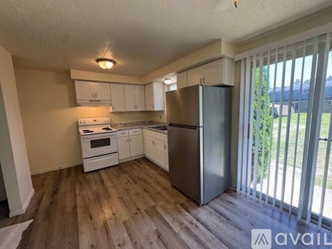 A kitchen with a refrigerator, stove, and cabinets.