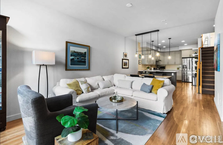 A modern living room with a grey armchair, a white sofa, and a coffee table with a plant on it.