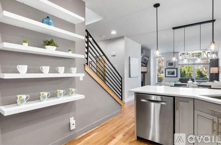 A kitchen with a stainless steel dishwasher and white shelves.