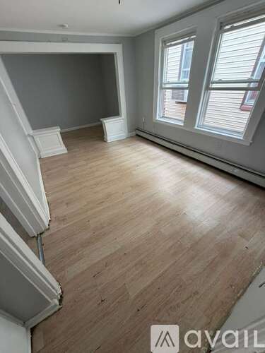 A room with wooden flooring and a window with blinds.