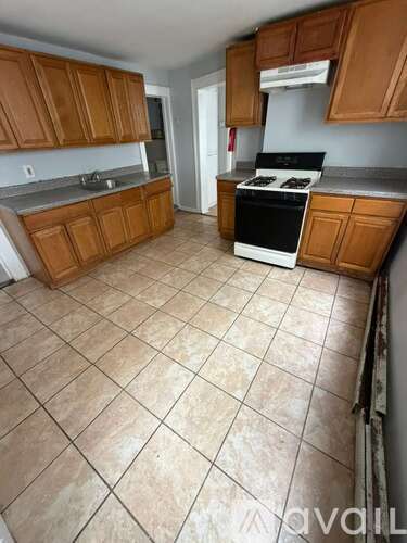 A kitchen with brown cabinets and a tiled floor.