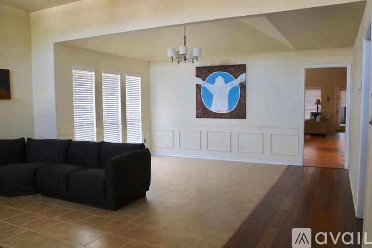 A living room with a black couch and a painting on the wall.