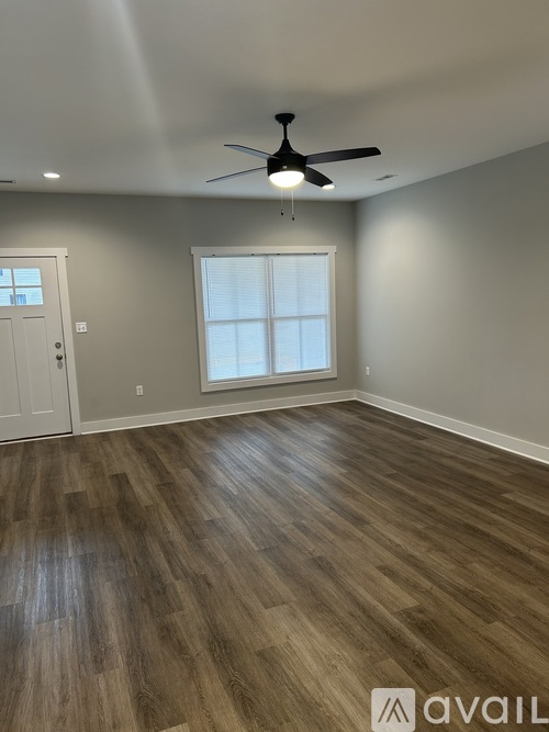 A room with a ceiling fan and wooden flooring.