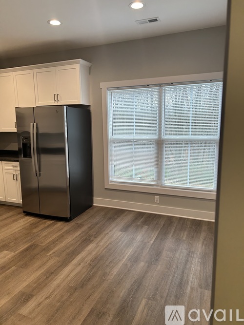 A kitchen with a black refrigerator and white cabinets.