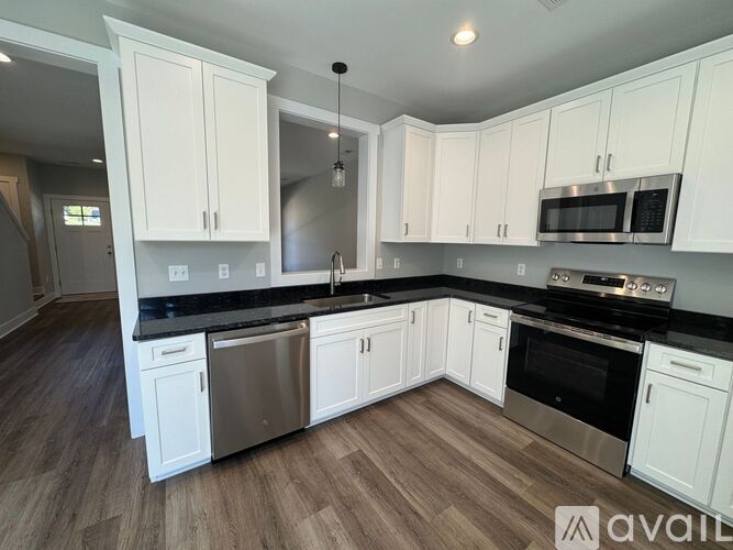 A kitchen with white cabinets and a black countertop.