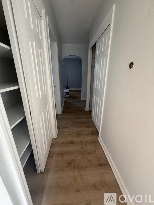A long hallway with white doors and shelves on the left.