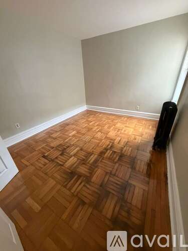 A room with wooden flooring and a wall on the right side.