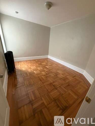 A room with wooden flooring and white walls.