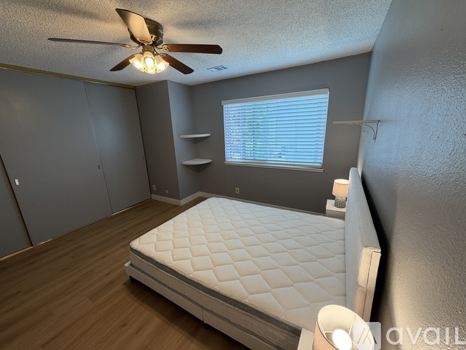 A bedroom with a bed, a ceiling fan, and a window with blinds.