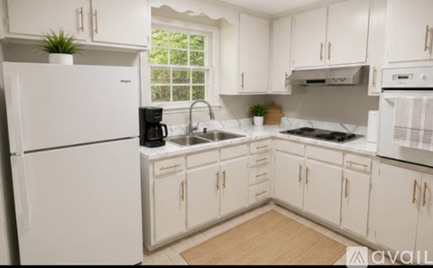 A white kitchen with a refrigerator, sink, and stove.