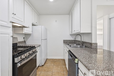 A kitchen with white cabinets and a granite countertop.