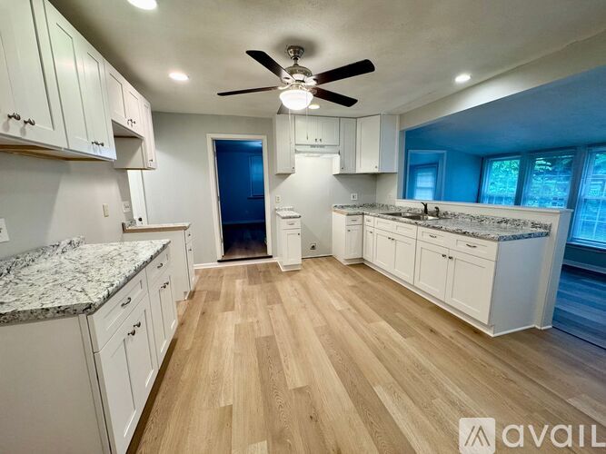 A kitchen with white cabinets and a marble countertop.