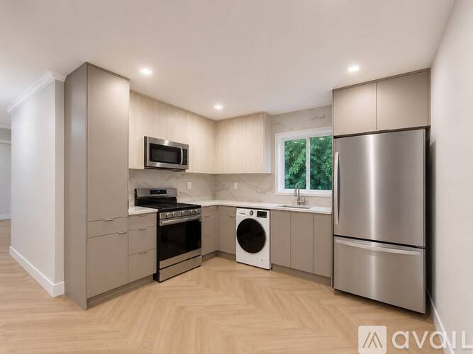 A modern kitchen with stainless steel appliances and wooden flooring.