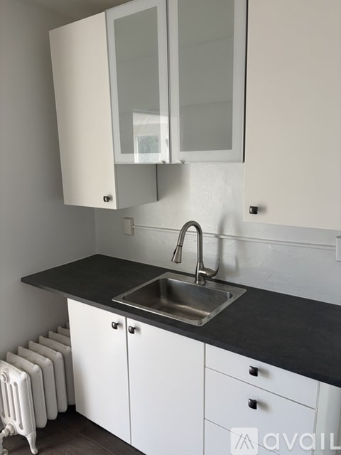 A kitchen with white cabinets and a black countertop.