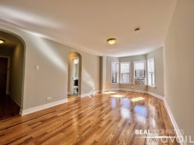 A spacious room with wooden flooring and a large window.