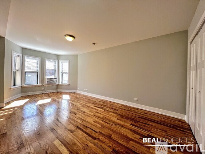 A room with wooden flooring and a window with blinds.