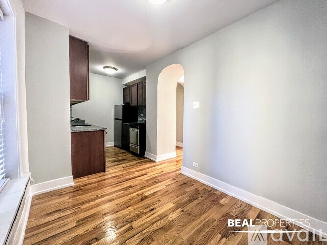 A kitchen area with wooden floors and a refrigerator.