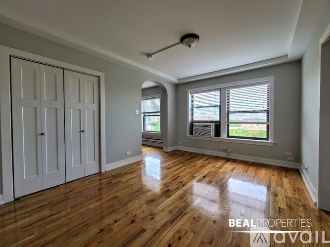 A room with wooden floors and a large window with blinds.