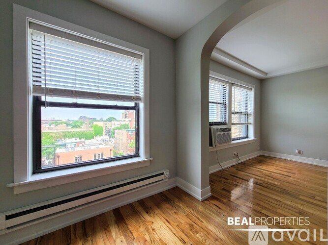 A room with wooden floors and two windows with blinds.
