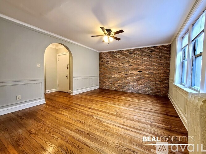 A room with wooden floors and a brick wall.