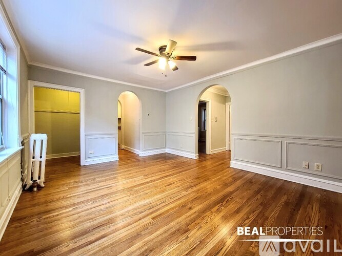 A spacious room with wood flooring and a ceiling fan.