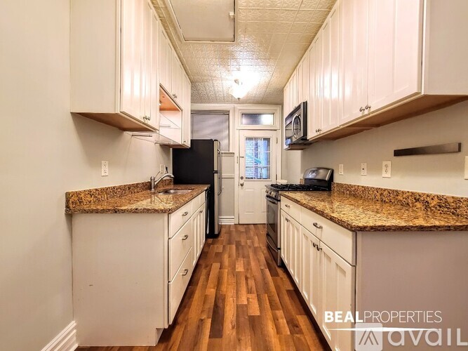 A kitchen with white cabinets and granite countertops.