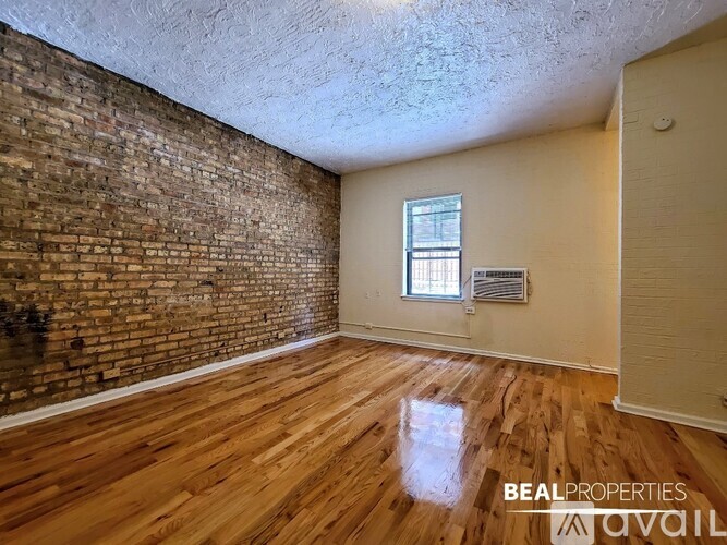 A room with wooden floors and a brick wall.