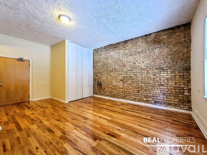 A room with wooden floors and a brick wall.