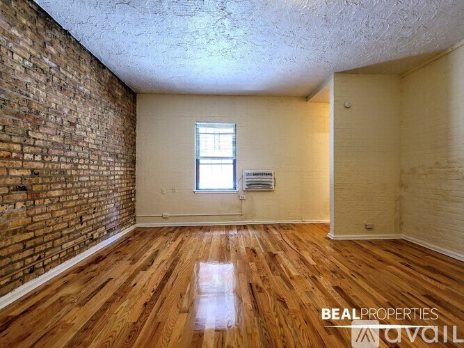 A room with wooden floors and a brick wall.