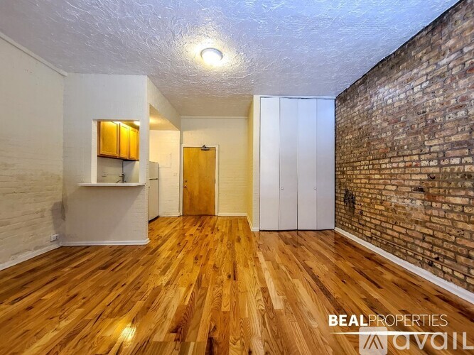 A room with wooden floors and a brick wall on one side.