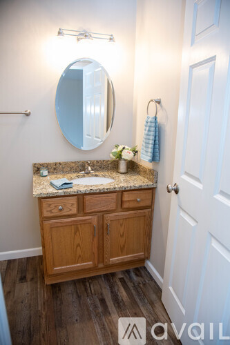 A bathroom with a wooden vanity and a round mirror.