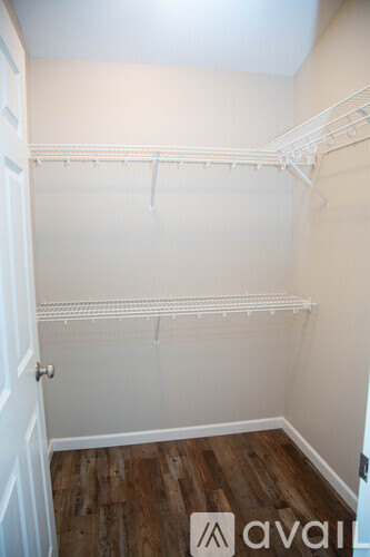 A white closet with a wooden floor and a door.