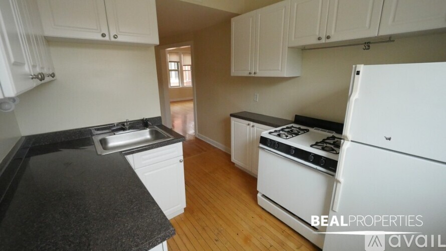 A kitchen with white cabinets and black countertops.
