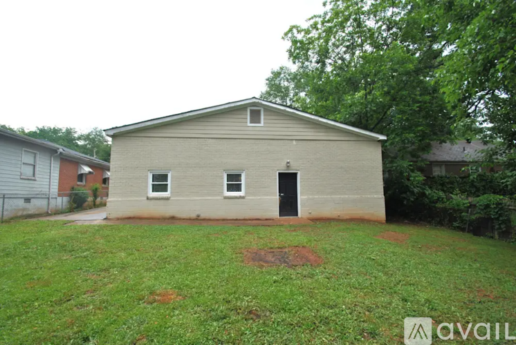 A small building with a black door is surrounded by a grassy area.